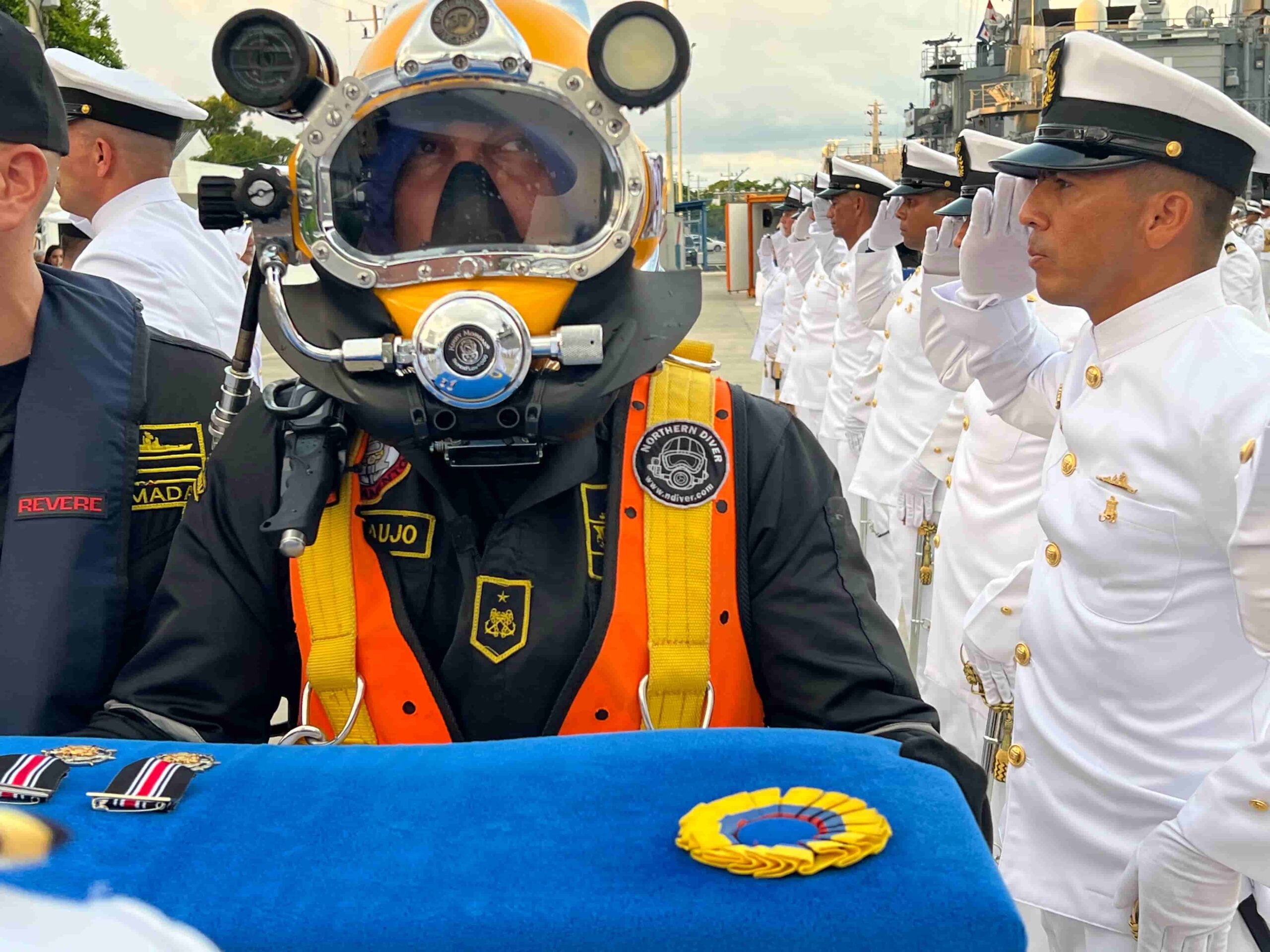 Buzo de la Armada lleva las medallas a los condecorados.